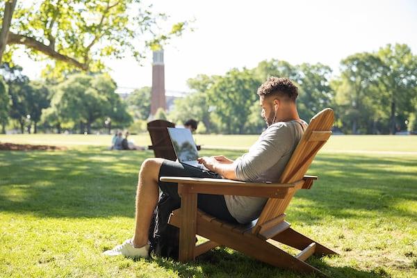 A student works on a laptop on the quad.